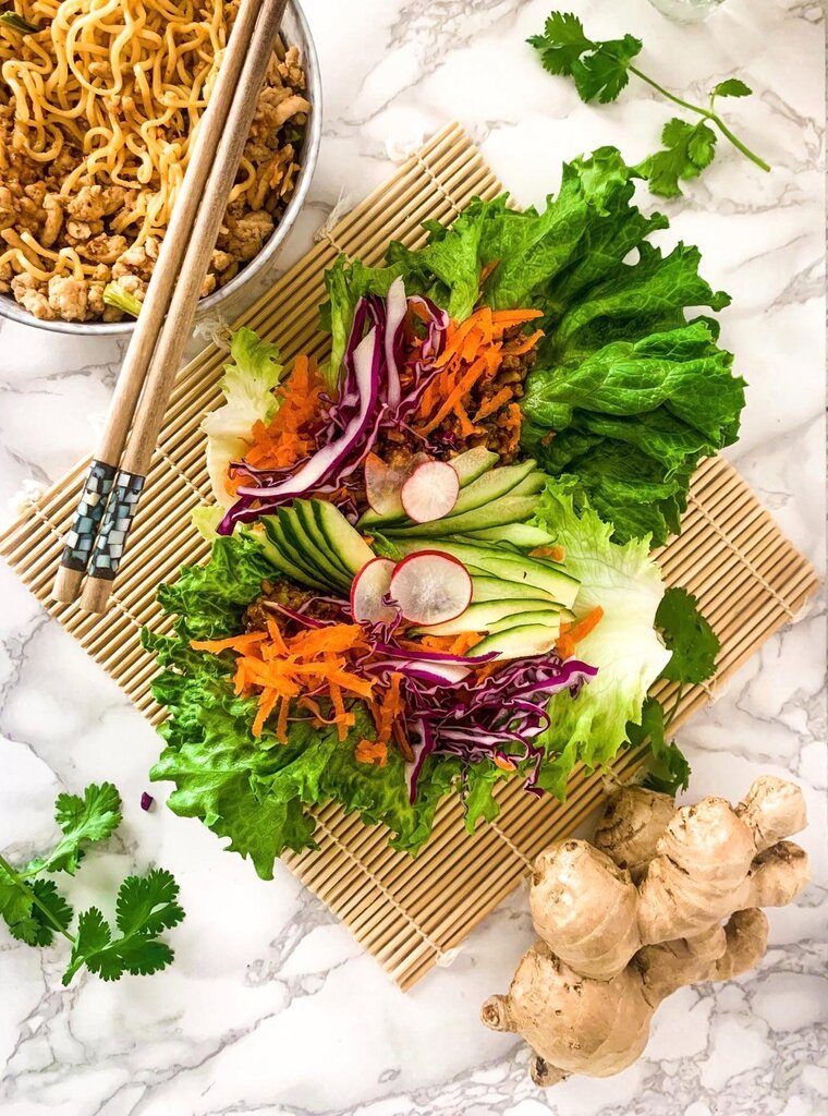 Peanut chicken lettuce wraps overhead view with carrots, radish, and cucumber