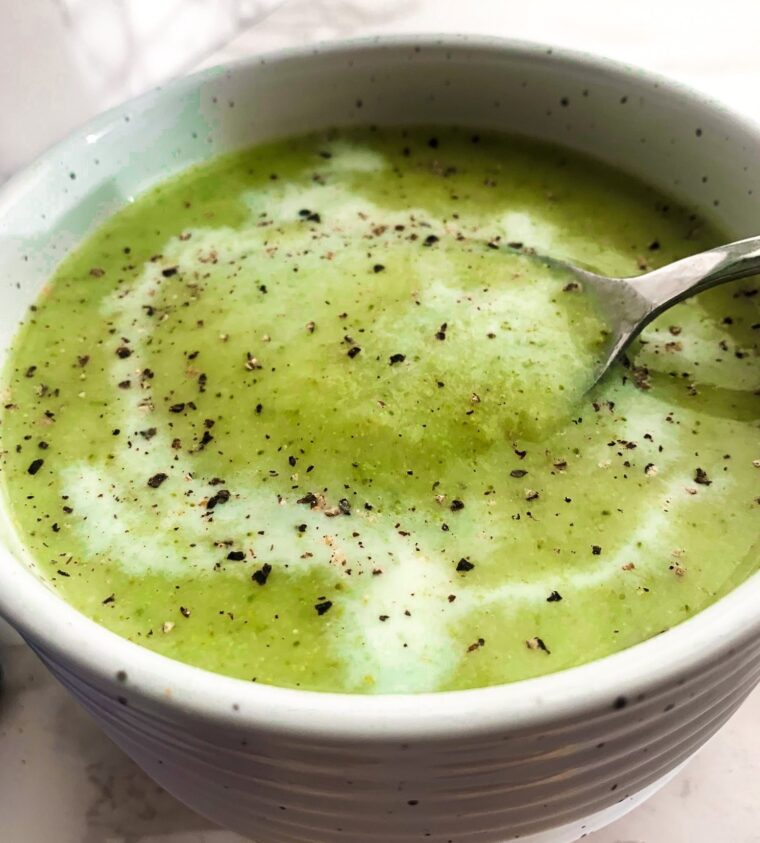 broccoli soup in a bowl with spoon lifting out of soup