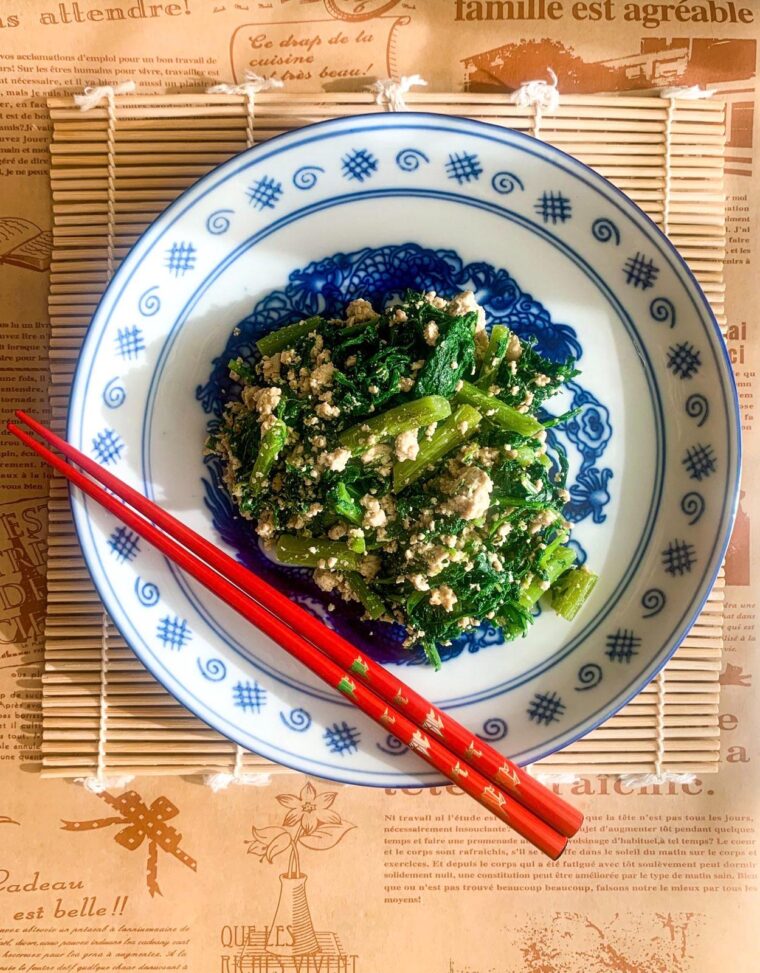 Shungiku shiraae salad with crumbled tofu on a wooden placemat