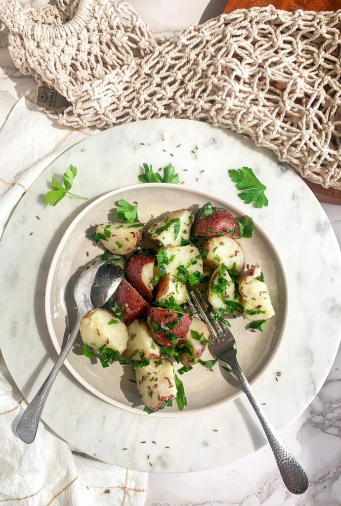 potato, caraway and parsley salad with fork on marble tray